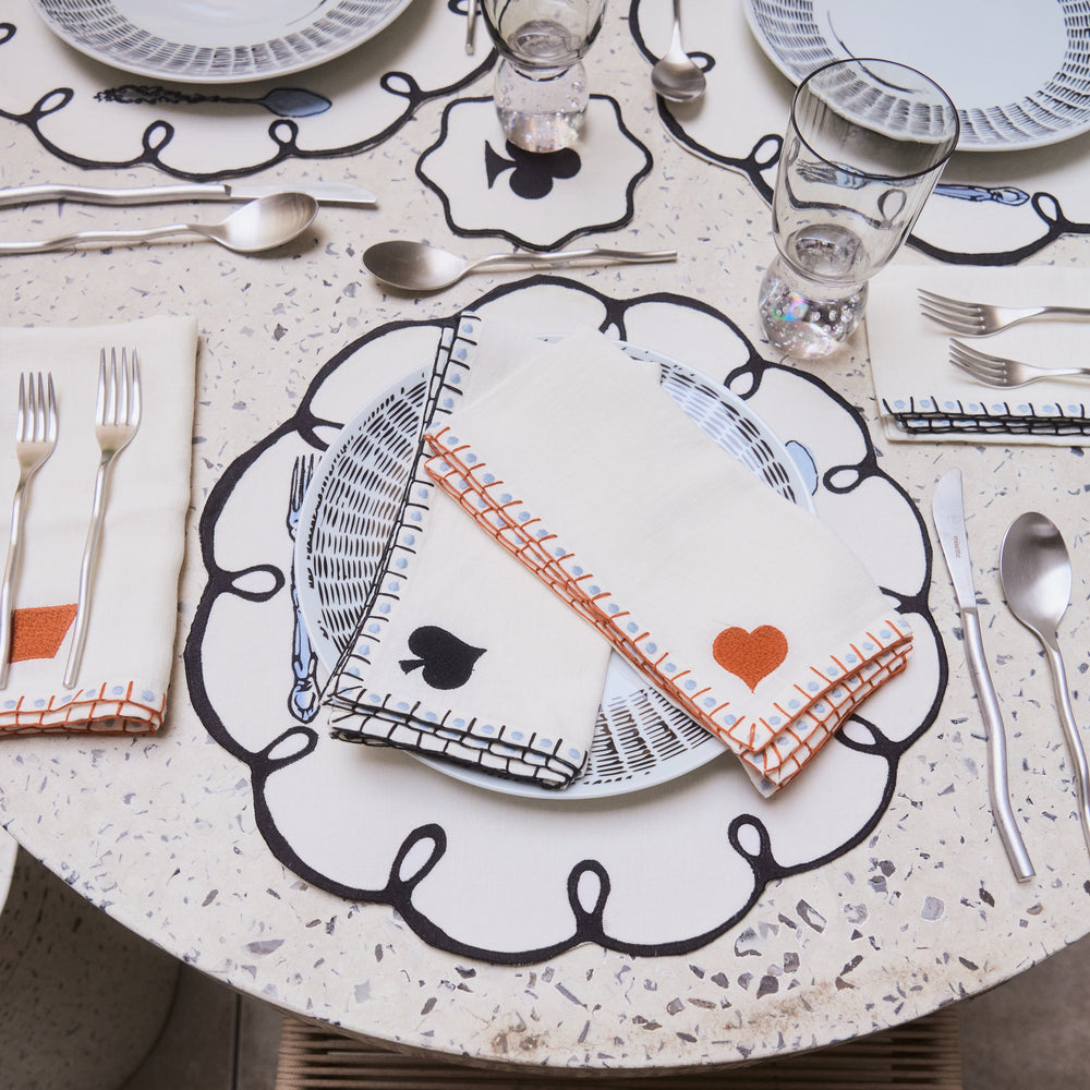 Dining table setting with decorative plates, cutlery, and napkins on a terrazzo-style surface.