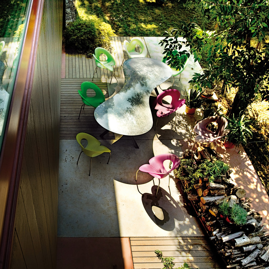 Rooftop or terrace with multiple colored chairs around a curvy white table.