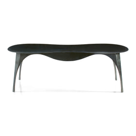 Close-up image of a dark curved-edged oval bench or table with sculptural legs.