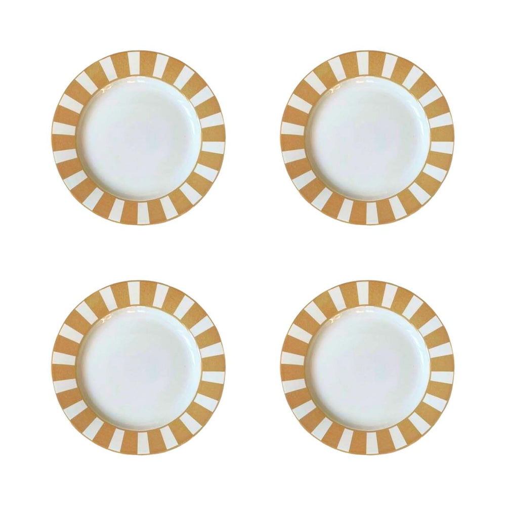 Four white plates with gold and white striped rims on a white background