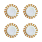 Four white plates with gold and white striped rims on a white background