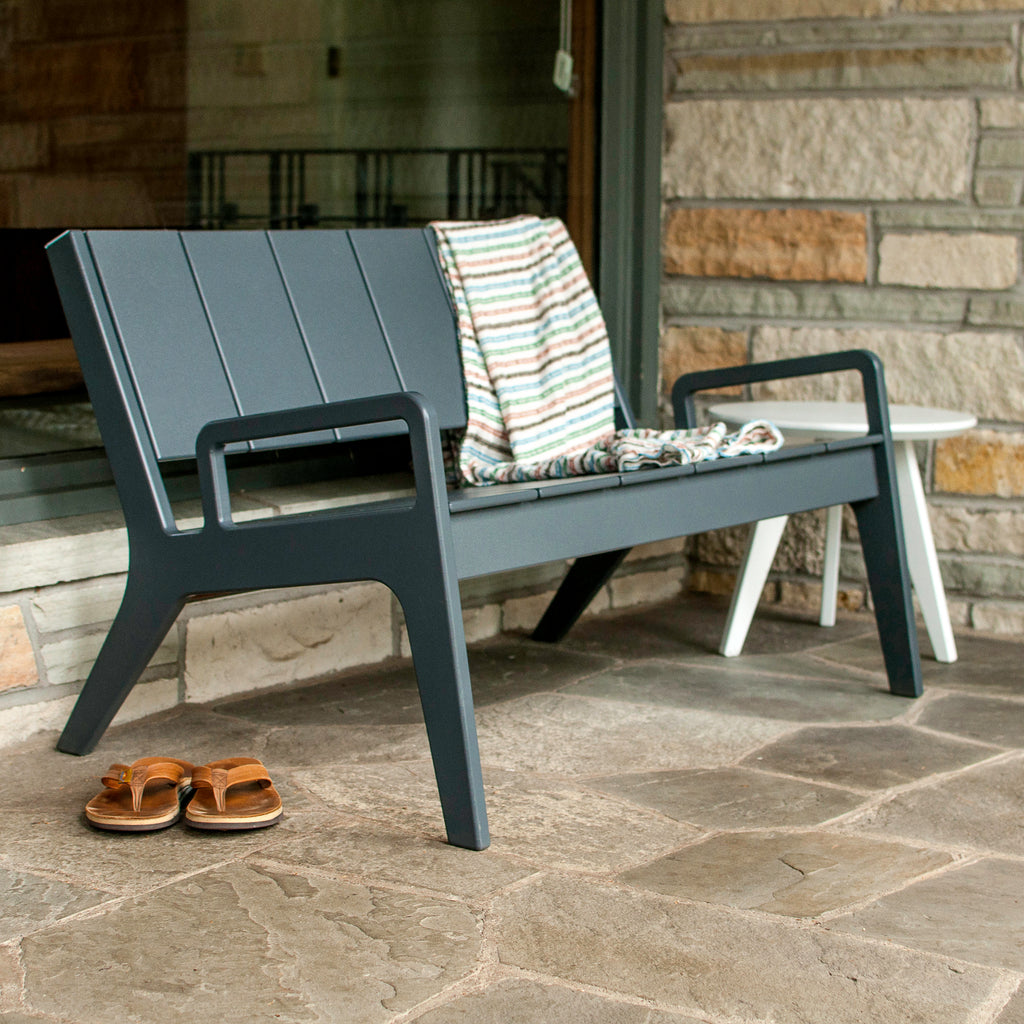 Dark blue/gray outdoor bench with slatted back and matching frame, cushions draped
